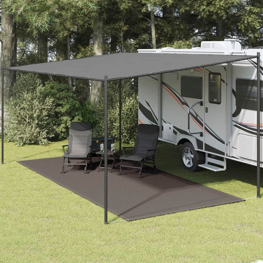 Outdoor patio setup with black tent carpet, deck chairs, and RV, perfect for camping comfort and relaxation.