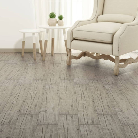 Self-adhesive PVC flooring planks in oak washed style, enhancing a cozy living space with a beige armchair and side table.