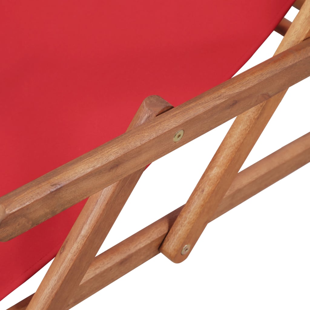Close-up of the wooden frame of a folding beach chair with red fabric seat.