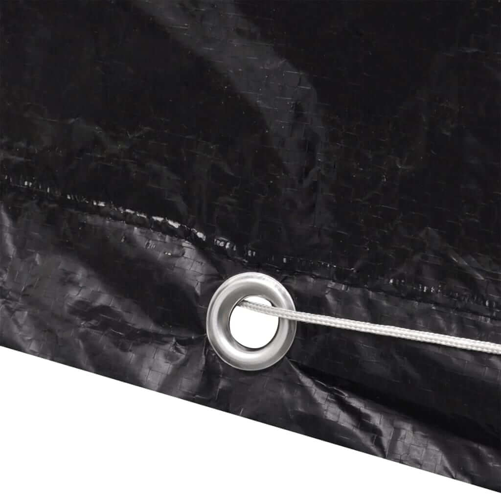 Close-up of black polyethylene garden furniture cover showing aluminium eyelet and fastening rope for secure fit.