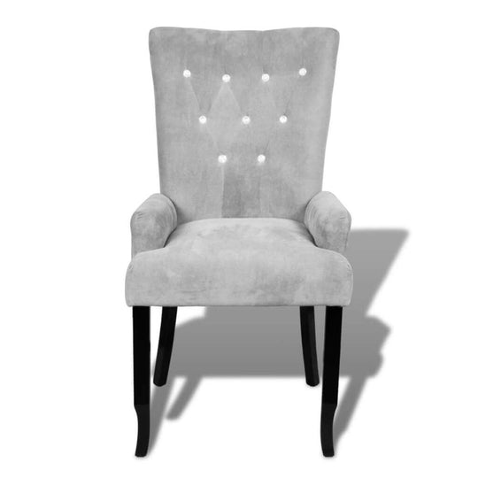 Elegant silver velvet armchair with button detailing and dark wooden legs, perfect for stylish lounge or dining settings.