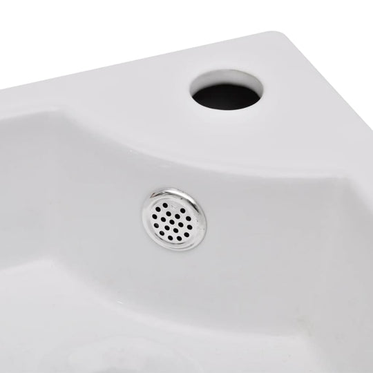 Close-up of a white ceramic wash basin with overflow and chrome drain, designed for contemporary bathrooms.