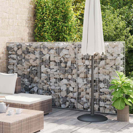 Gabion basket with lids made of galvanised wire, filled with stones, used as a retaining wall in a landscaped patio.