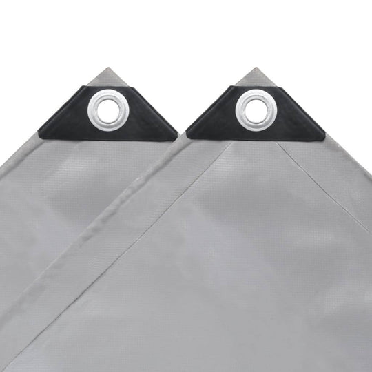 Close-up of grey heavy-duty tarpaulin corners with grommets, designed for durability and outdoor use.