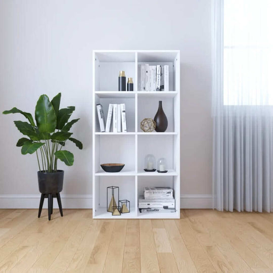 White book cabinet with 8 compartments and decorative items, surrounded by indoor plants in a modern living space.