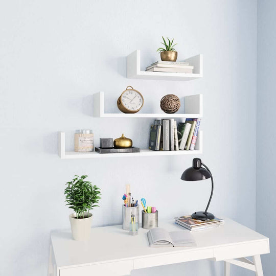 Modern white wall display shelf set with books, decorative items, and plants, enhancing a stylish workspace.