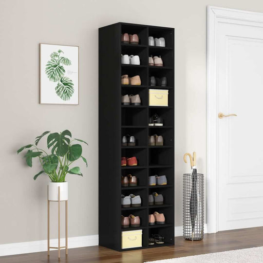 Black shoe cabinet with 22 compartments, stylishly arranged in a living space alongside a plant and decor items.