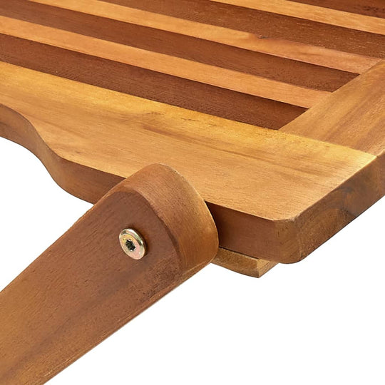 Close-up of a folding outdoor chair made of solid acacia wood, showcasing its durable slatted design and sturdy hinge.