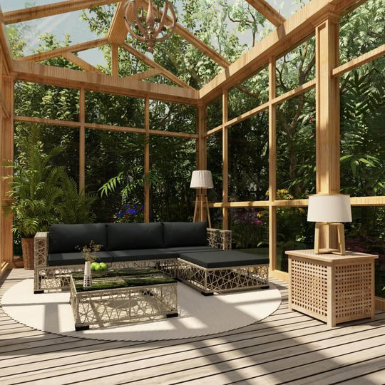 Stylish outdoor lounge set with black cushions in a garden conservatory, featuring a coffee table and decorative lamp.