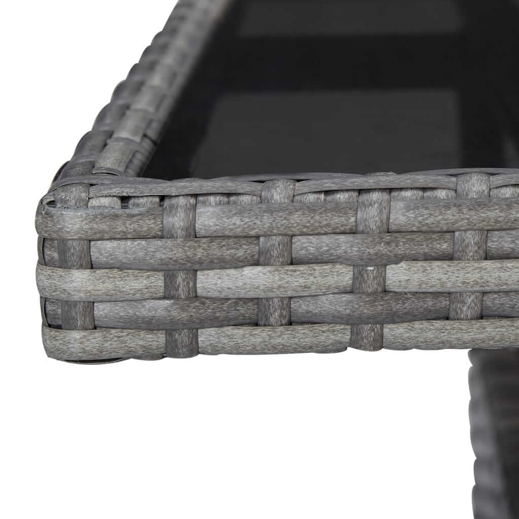 Close-up of grey poly rattan weave on outdoor dining table with glass top, showcasing durable and stylish design.