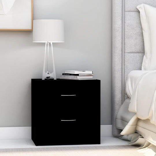 Black bedside cabinet with two drawers, modern lamp, and books beside a cozy bed in a stylish bedroom setting.