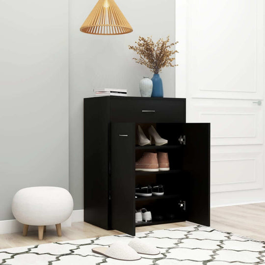 Black shoe cabinet with drawer and open door displaying shoes, styled in modern living space with decor elements.