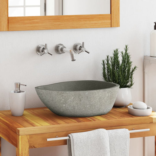 Oval river stone basin on wooden countertop in modern bathroom setting.