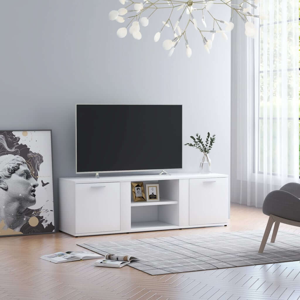 White engineered wood TV cabinet with two doors and two open compartments, holding decor items and positioned in a stylish, bright living room.