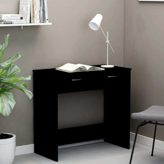 Modern black desk with drawer, perfect for compact spaces, paired with a stylish lamp and indoor plants. Ideal for study or work area.