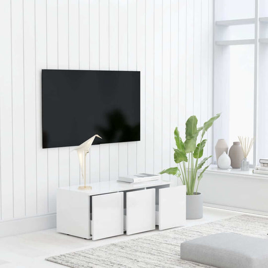 Modern white TV cabinet with three drawers, indoor plants, and a black TV on a stylish wall. Perfect furniture for lounge decor.