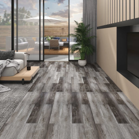 Self-adhesive PVC flooring planks in a modern living room with lounge furniture and large windows.