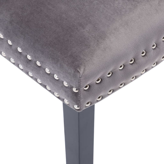 Close-up of grey velvet dining chair with decorative metal rivets and solid rubberwood legs. Ideal for classic dining areas.