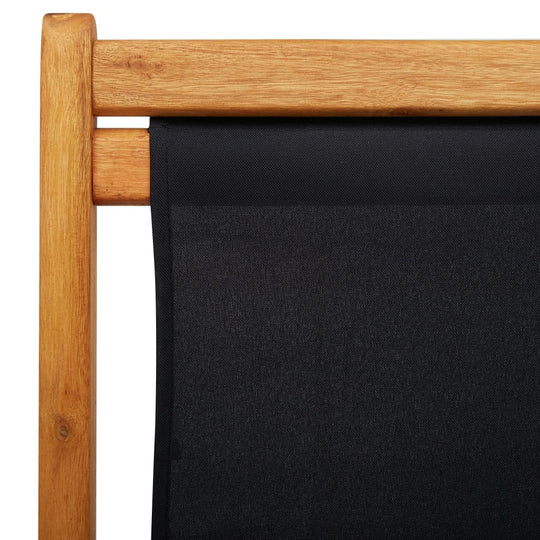 Close-up of folding beach chair with eucalyptus wood frame and weather-resistant black fabric seat. Ideal outdoor furniture.