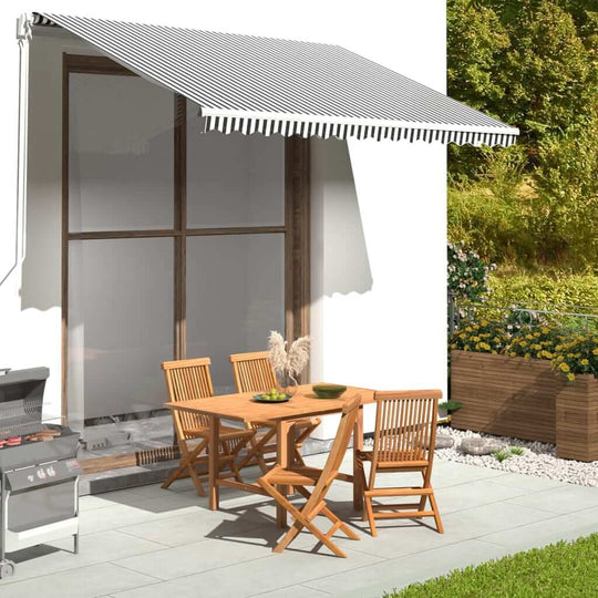 Outdoor dining area with an anthracite and white awning, wooden furniture, and a garden backdrop. Perfect for patio relaxation.