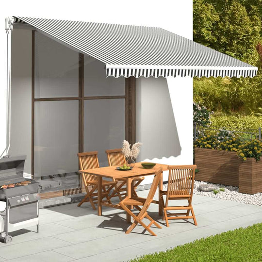 Replacement awning fabric in anthracite and white, providing shade over patio furniture in a garden setting.