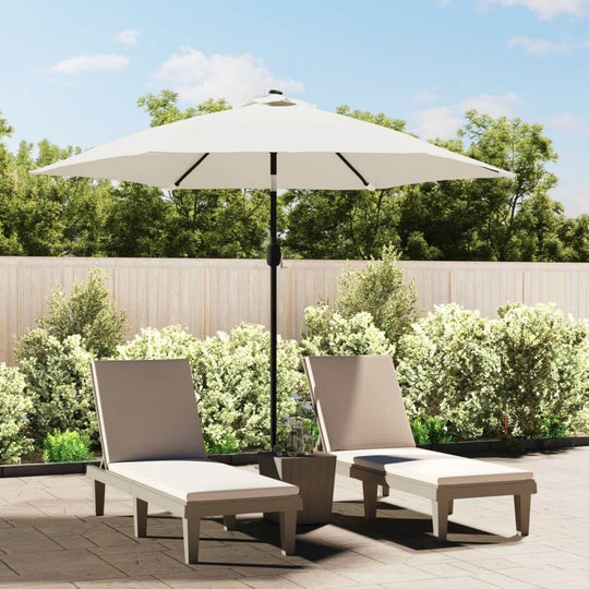 Outdoor lounge area with sand white parasol providing shade over two loungers, surrounded by greenery.