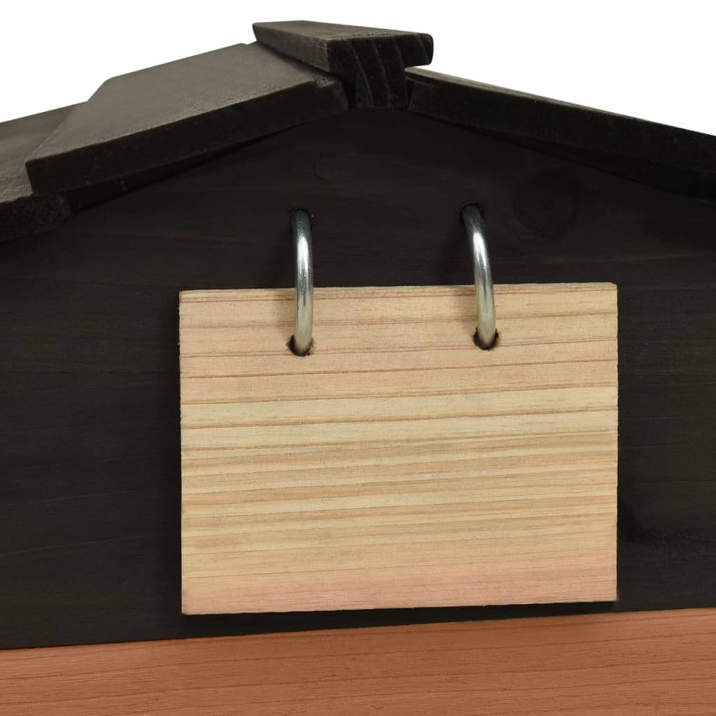 Wooden sign with metal rings attached to the roof of a black and brown garden shed for lawn mower storage.