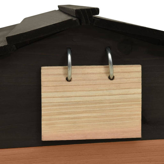 Wooden sign with metal rings attached to the roof of a black and brown garden shed for lawn mower storage.