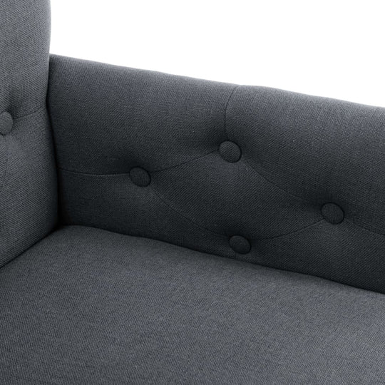 Close-up of a dark gray fabric dining chair with armrests and button tufting for added style and comfort.