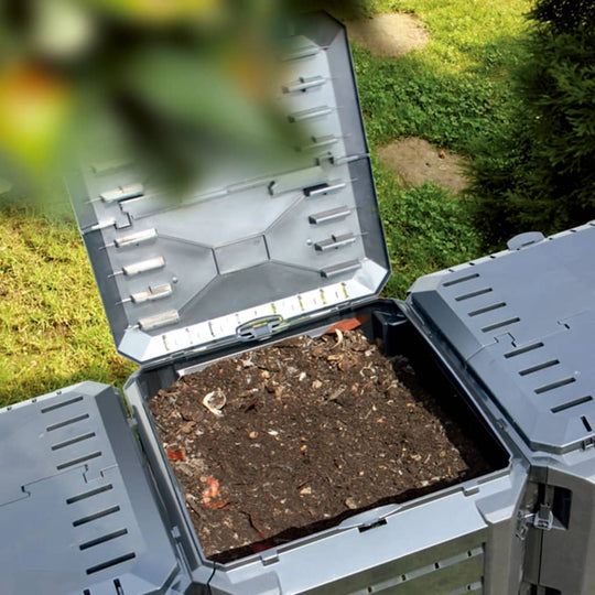 Black garden composter bin open, showcasing organic matter for efficient decomposition and fertilizer production in the garden.