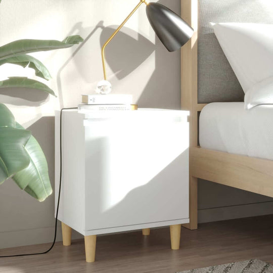 Bed cabinet with solid wood legs in white, featuring a lamp and plant, styled in a Scandinavian interior. Perfect for bedroom storage.