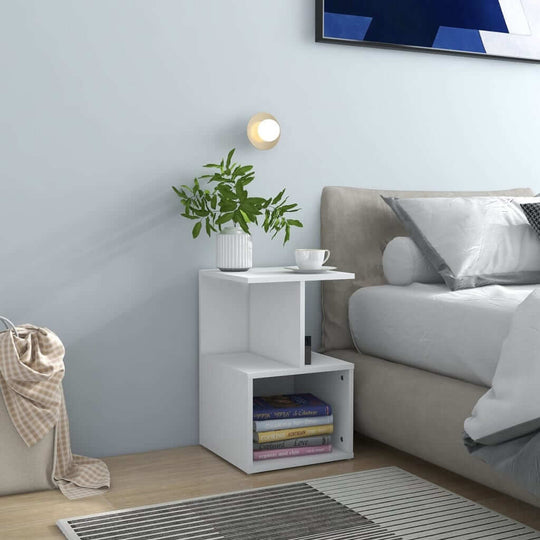 White bedside cabinet with open compartments, plant, and decor beside a stylish bed, ideal for organized living spaces.