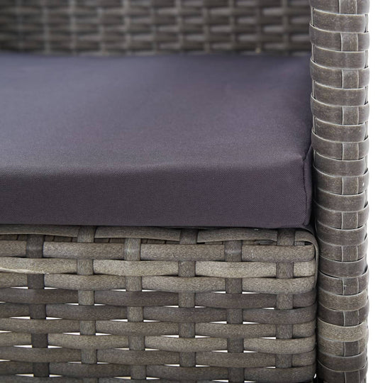 Close-up of dark grey cushion on a poly rattan garden chair, showcasing durable outdoor furniture design.