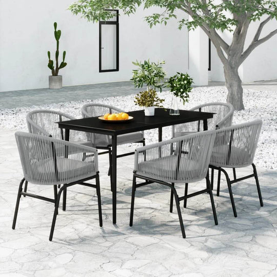 7 Piece grey garden dining set featuring glass tabletop and durable PVC rattan chairs in an outdoor setting.