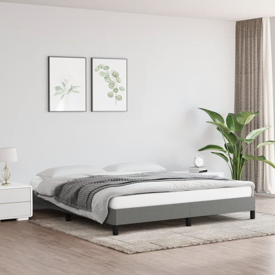 Dark grey super king bed frame without mattress in modern bedroom setting with plants and wall art.