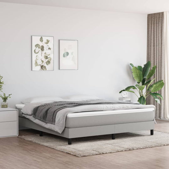 Light grey super king bed frame without mattress in modern bedroom with plants and artwork, offering a cozy atmosphere.