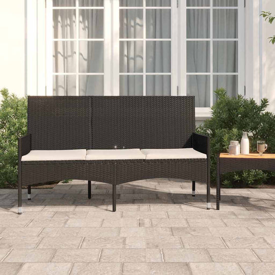 3-seater black poly rattan garden bench with cushions in an outdoor setting, surrounded by greenery. Perfect outdoor furniture piece.