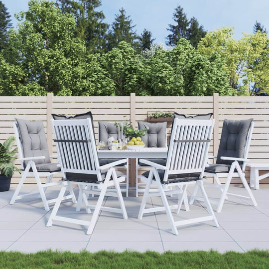 Outdoor dining area with highback chairs and table, surrounded by greenery and modern fencing. Perfect for entertaining.