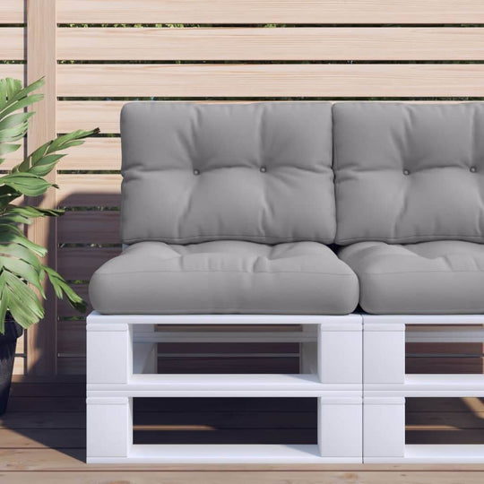 Grey outdoor pallet cushion on a modern lounge sofa with a plant backdrop, enhancing outdoor furniture aesthetics.