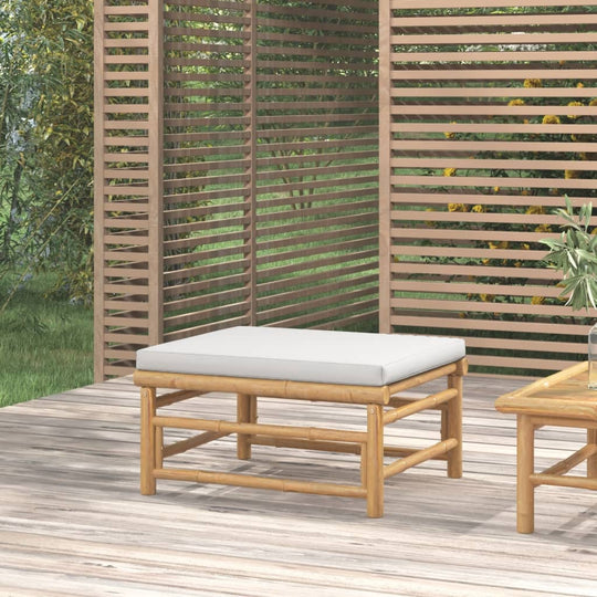 Elegant bamboo garden footstool with light grey cushion, perfect for outdoor relaxation and comfort.