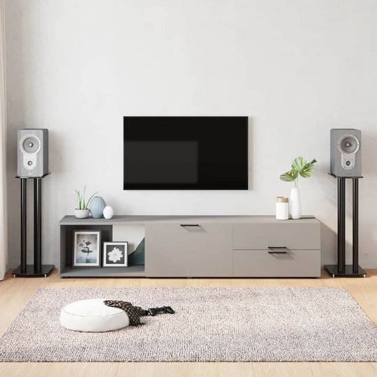 Modern living room featuring speaker stands with black tempered glass pillars, stylish furniture, and a sleek TV setup.