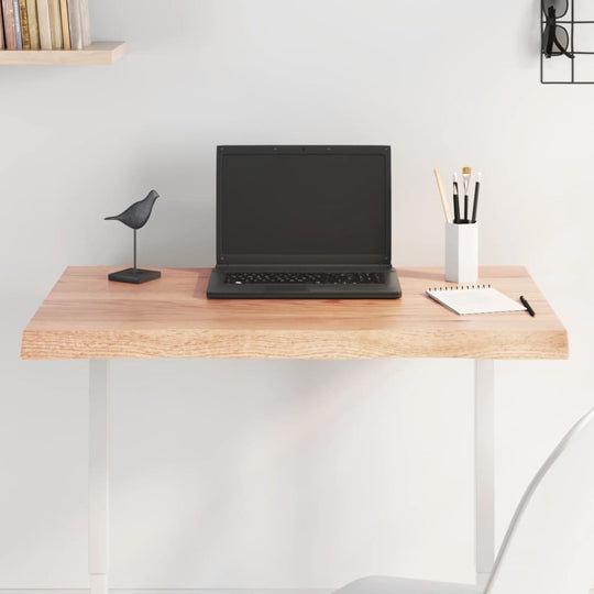 Modern desk setup with light brown table top, laptop, stationery, and decorative bird figurine for stylish workspaces.