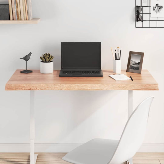 Modern workspace featuring a light brown wooden desk, laptop, plants, and decor for a stylish home office.