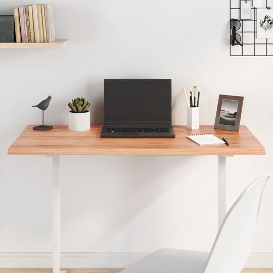 Modern workspace featuring a light wood desk with a laptop, stationery, and decorative items in a bright setting.