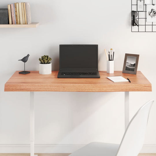 Modern desk with light wood tabletop, laptop, and decorative items on a minimalist workspace.