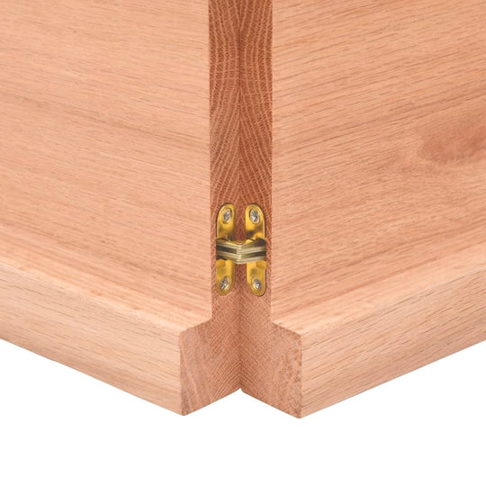 Close-up of a wooden table edge with brass hinge, showcasing the solid construction and design detail for furniture.