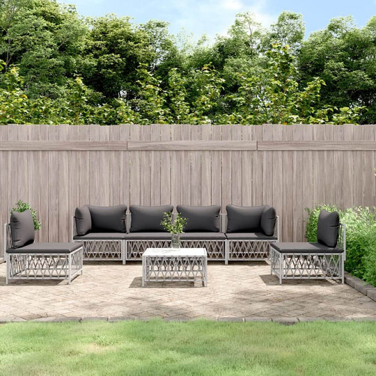 7 piece outdoor lounge set with black cushions on a patio, overlooking a wooden fence and greenery.