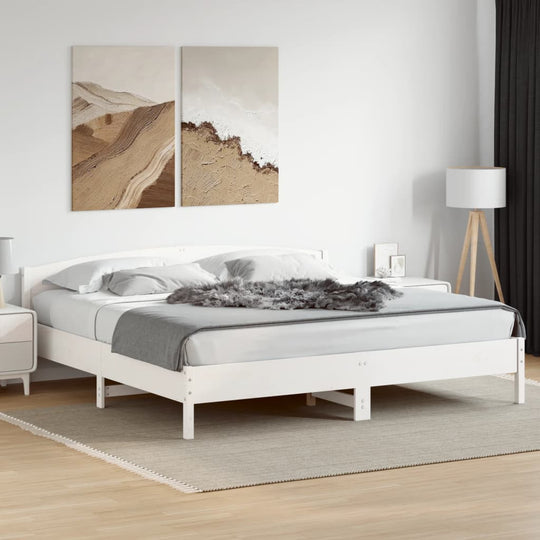 Modern white bed frame without mattress in a stylish bedroom setting, featuring solid pine wood and decorative artwork.