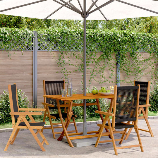 Outdoor dining set with four reclining chairs and a table under a large umbrella, surrounded by greenery.