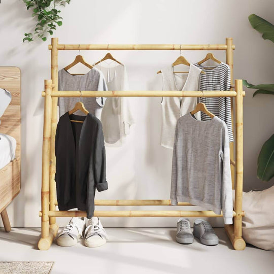 Bamboo clothes rack with hanging clothes and shoes, showcasing ample storage and modern design in a cozy room setting.